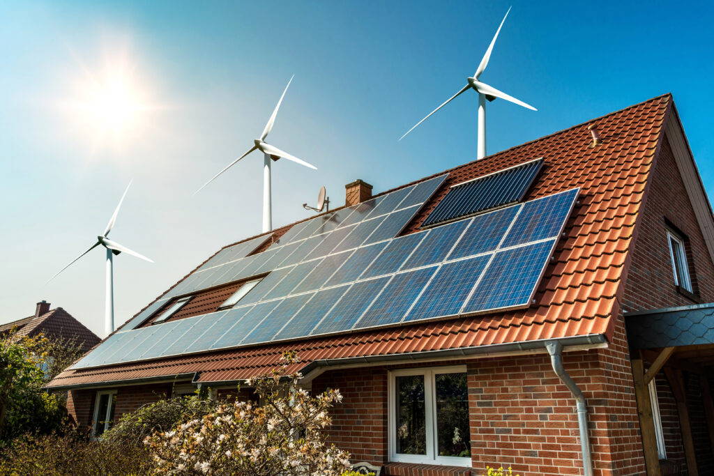 An image of a house with a clay roof with solar panels and wind turbines.