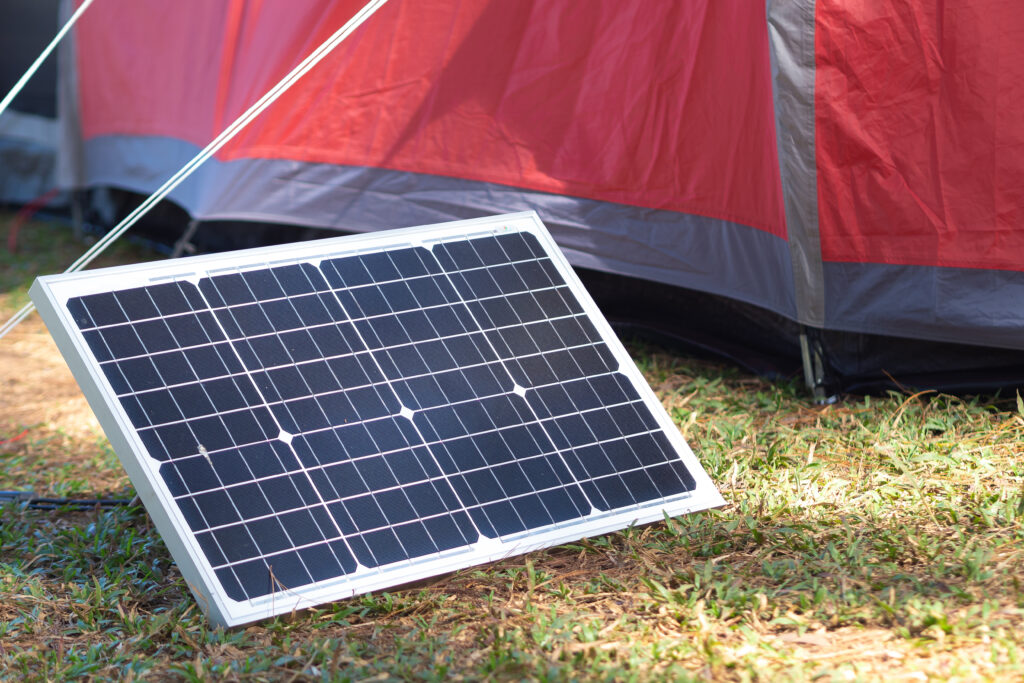 A solar panel set up next to a tent.