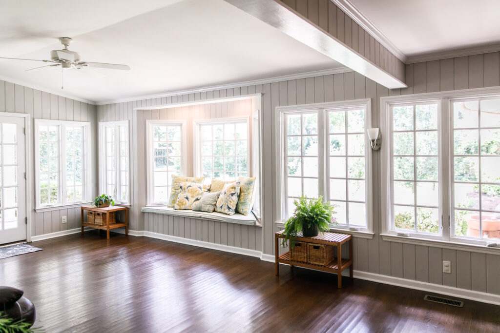 An image of a living room with lots of windows looking out into the backyard. 