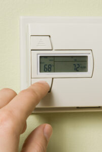 A person changing the temperature on a thermostat.