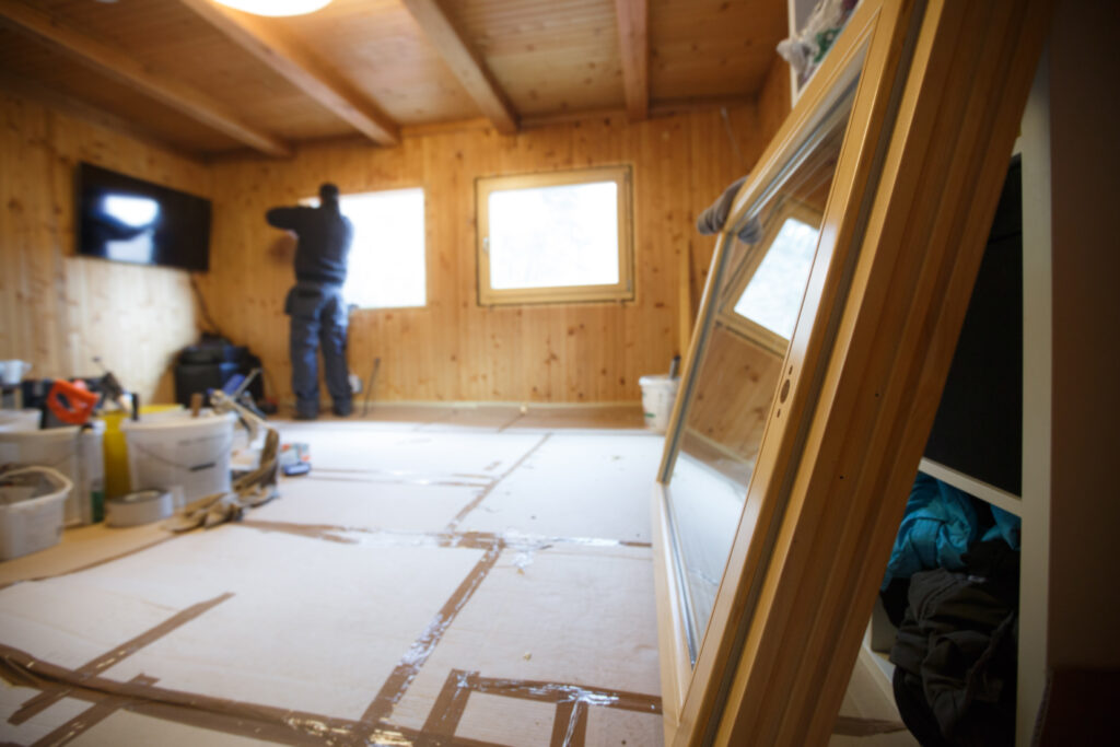 A picture of a person installing windows into a house.