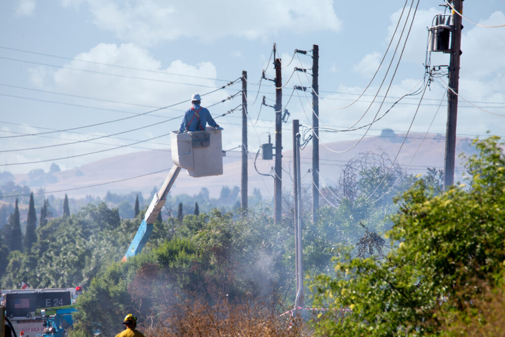 A person on a crane looking out over a smoky forest.