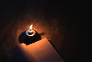 A book lit by a single candle.