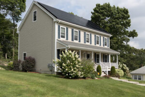 A picture of a house with black roof and black solar panels.