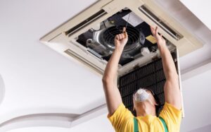 A person repairing and HVAC unit in his ceiling.