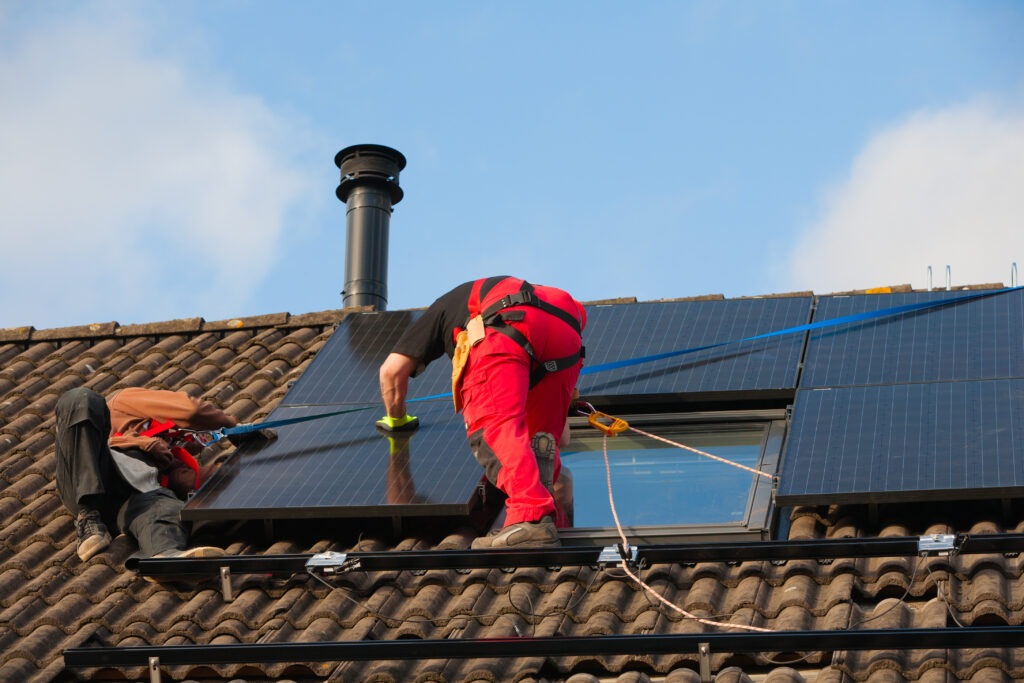 Two technicians perform a solar panel installation on a California roof.