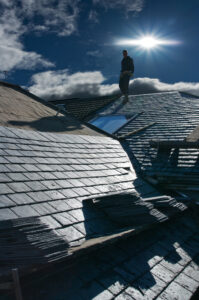 A man installing slate panels onto a roof.