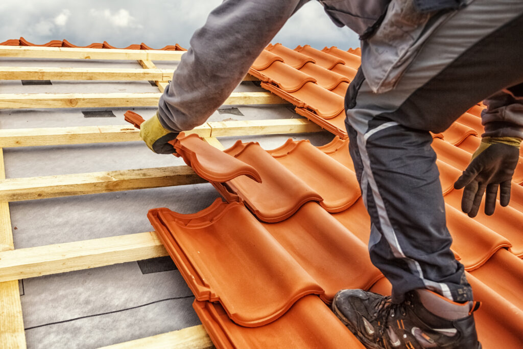 Roofer at work, installing clay roof tiles