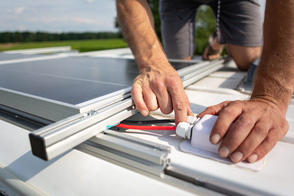 A person installing solar panels onto the roof of their RV.