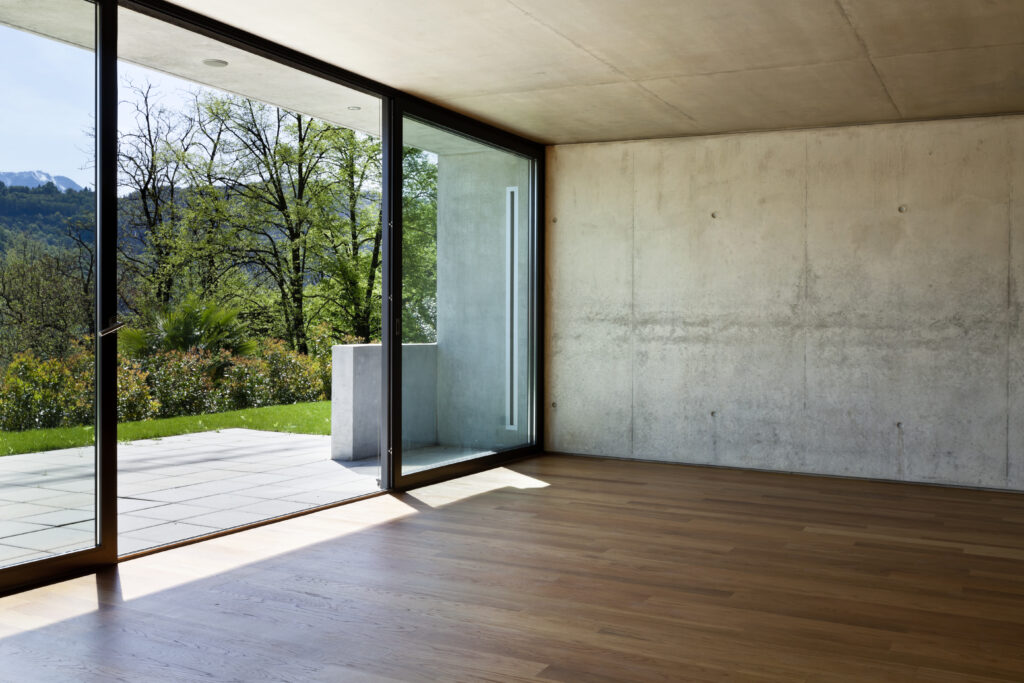 A wall fo windows looking out over a patio with a beautiful view of snowy mountains.